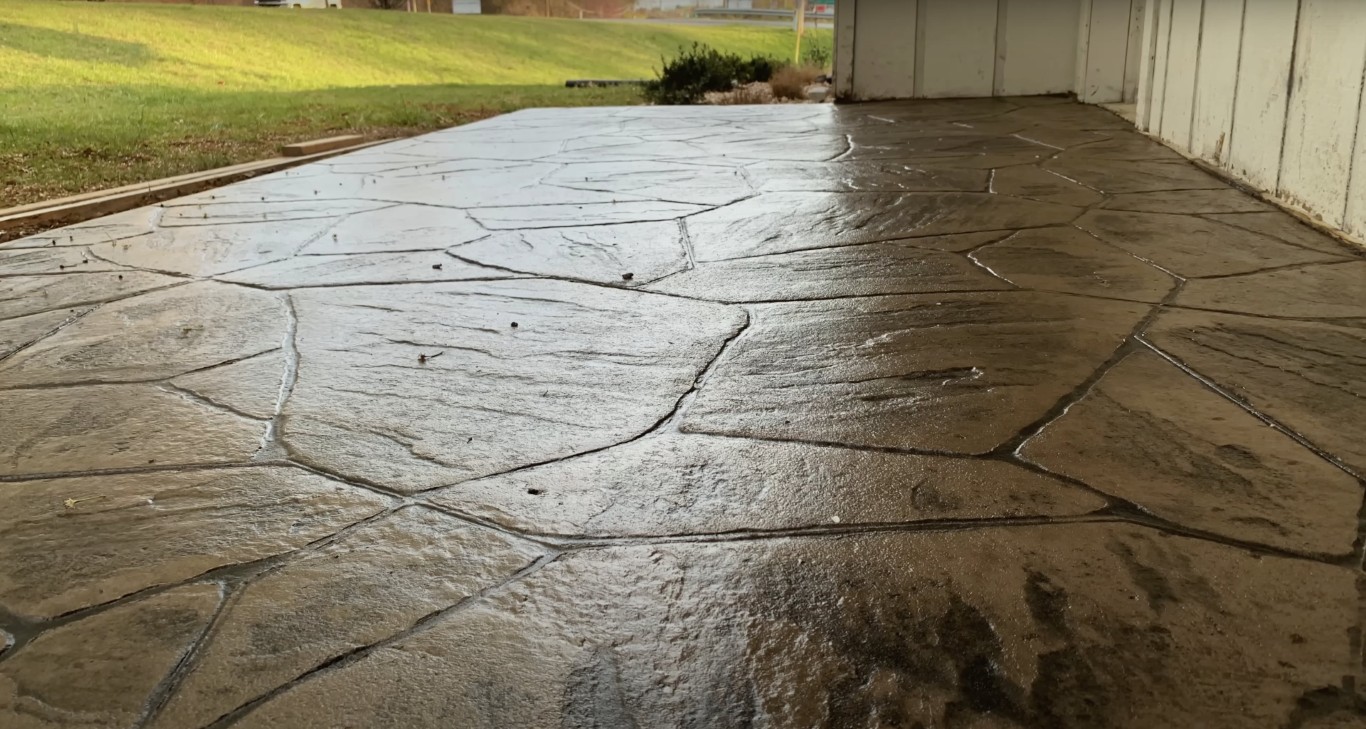 Stamped concrete patio with flagstone texture pattern installed outside a residential garage